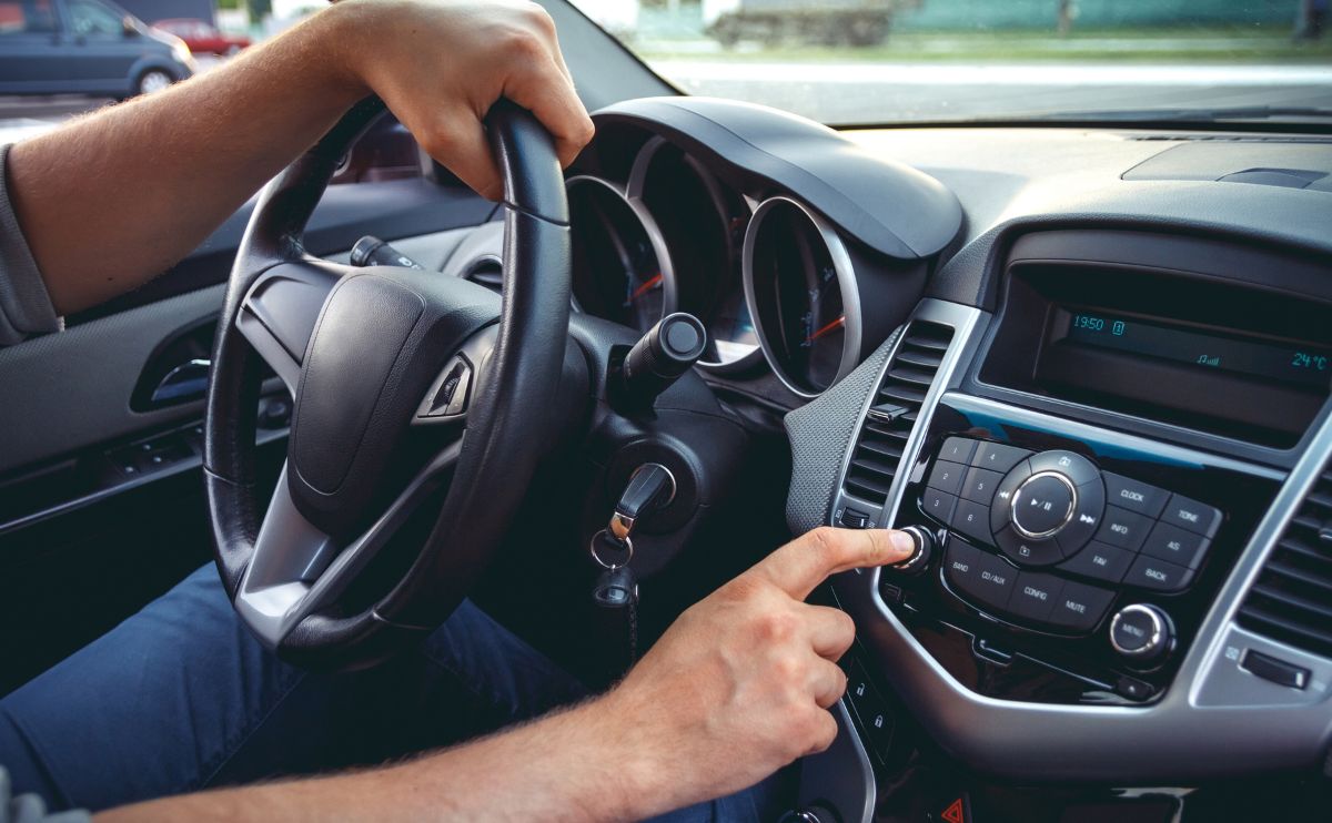 A person is driving in the car and pointing to the steering wheel.